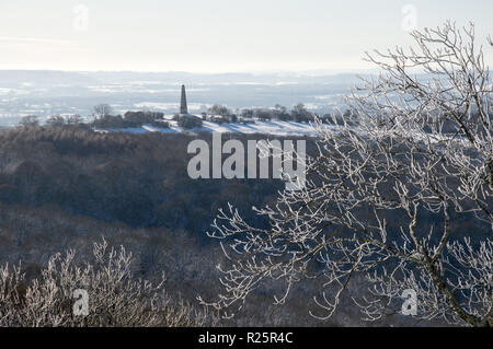 Un arbre couvert de neige avec un monument situé sur l'arrière-plan dans la campagne anglaise sous le soleil d'hivers jour Banque D'Images