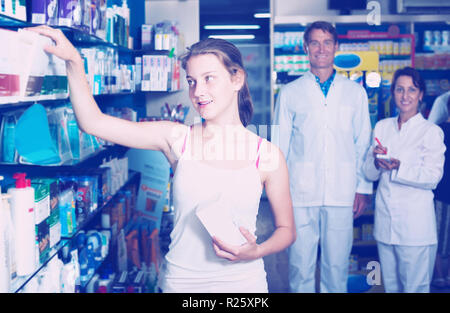 Cheerful teenager Girl standing with drug store produits en mains en pharmacie Banque D'Images