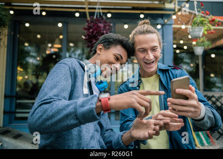 Les jeunes hommes heureux positifs bénéficiant de nouvelles technologies Banque D'Images