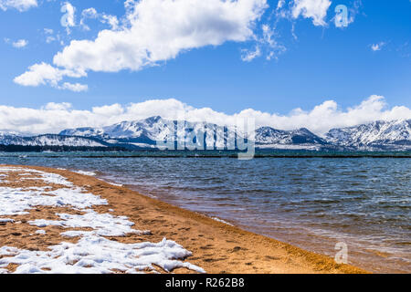 Rivage de lac Tahoe sud, couvert de neige et de sable, sur une journée ensoleillée, la neige a couvert la Sierra montagnes en arrière-plan ; Californie Banque D'Images