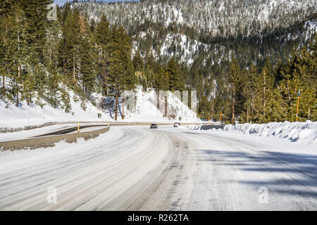 Roulant sur une route couverte de neige et de glace à travers les montagnes Sierra sur une journée ensoleillée, au Nevada Banque D'Images