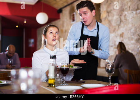 Exprimant son mécontentement en guest féminin parlant à l'alimentation s'excusant waiter Banque D'Images