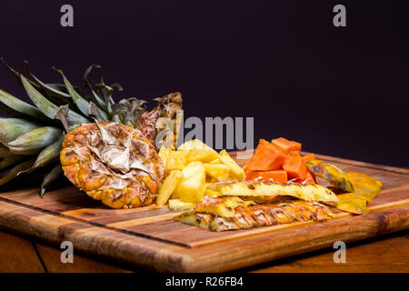 Ananas et papaye fraîchement coupé sur une planche à découper en bois. Banque D'Images