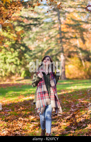 Une jeune femme brune dans un parc entouré de feuilles d'automne. Banque D'Images