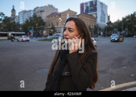 Young businesswoman marchant à travers la place et parler au téléphone Banque D'Images