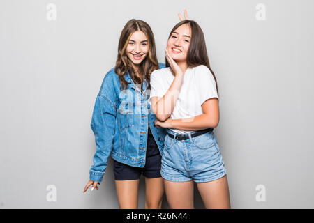 Portrait de deux jeunes femmes gaies Standing together and looking at camera isolated over grey background Banque D'Images