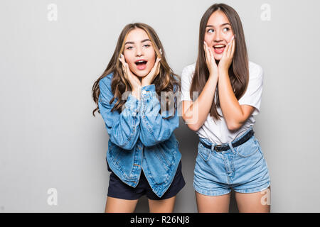 Portrait de deux beaux charmant happy se demande surpris girlfriends habillés en vêtements d'été, occasionnels isolé sur fond gris Banque D'Images