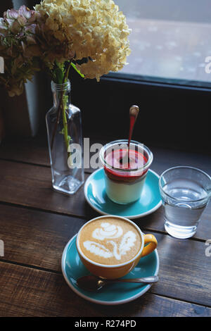 Gâteau au fromage avec du café dans un verre sur la table en bois Banque D'Images