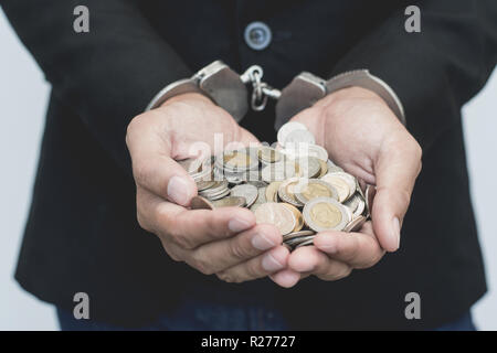 L'homme les mains dans des menottes avec thai monnaie. arrestation voler de l'argent conceptuel. Banque D'Images