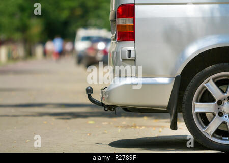 Close-up Vue de côté détail d'argent taille moyenne passager minibus de luxe van avec œillet de barre en stationnement sur la chaussée, rue de la ville ensoleillée d'été brouillée avec sil Banque D'Images