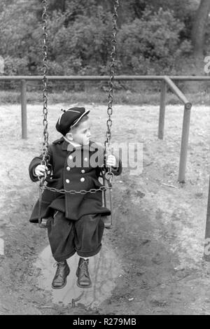 Jeune garçon assis sur une balançoire dans un parc 1950 Hongrie Banque D'Images