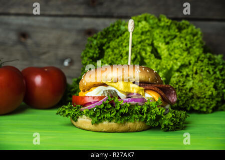 Délicieux cheesburger avec un grand nombre de légumes, moutarde, mayonnaise, de salami et d'oignon violet Banque D'Images