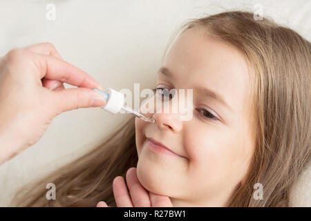 L'écoulement nasal chez les enfants. Maman s'égoutte dans le nez girl drops. Banque D'Images