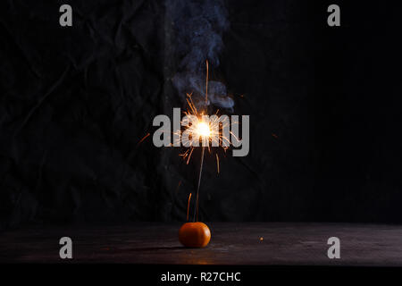 Sparkler dans la mandarine. Sparkler formant de belles étoiles de forme. L'obscurité est partout et l'effet de mousseux est étonnant. Symboles de la nouvelle année Banque D'Images