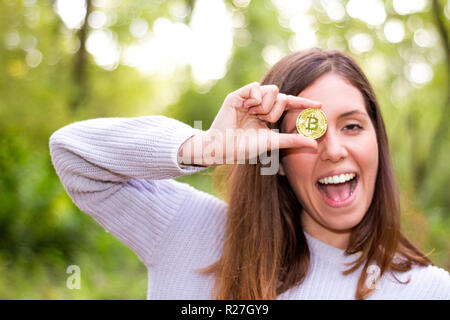 Young Caucasian woman holding a européenne ou bitcoin cryptocurrency smiling happy regarde droit devant lui, la bouche ouverte et un sourire parfait Banque D'Images