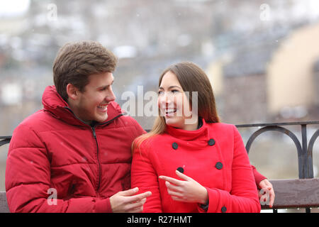 Heureux couple en rouge parle assis sur un banc en hiver Banque D'Images