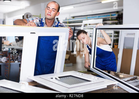 Aider les travailleurs expérimentés girl à travailler d'assemblage de fenêtres en PVC à l'usine Banque D'Images