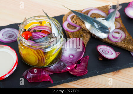 Pot d'anchois marinés maison avec l'oignon, betterave, poivron, vinaigre, citron, huile d'olive, sel de mer. Servi avec du pain de seigle sur la plaque d'ardoise Banque D'Images