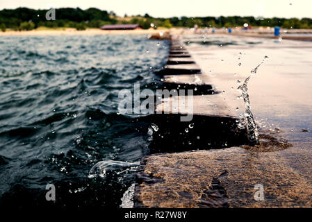 L'éclaboussure de vague sur jetty pier avec bornes métalliques. Au cours de la projection d'eau par temps couvert. Splash a gelé à l'embarcadère. USA, état du Michigan, Banque D'Images