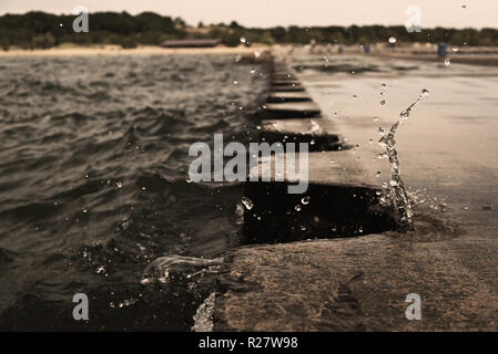 L'éclaboussure de vague sur jetty pier avec bornes métalliques. Au cours de la projection d'eau par temps couvert. Splash a gelé à l'embarcadère. USA, état du Michigan, Banque D'Images