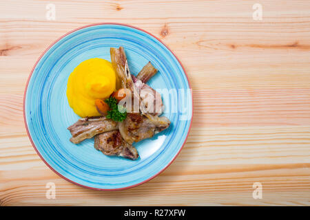 Vue de dessus du plat de fête traditionnel norvégien sur l'os de mouton servi sur la plaque de couleur avec purée de carottes caramélisées et suédois en bois sur backgrou Banque D'Images