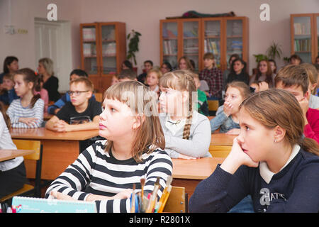 Les enfants de l'école dans la classe assis à leur bureau et l'écoute de l'enseignant Banque D'Images