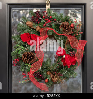 Couronne de Noël traditionnel accroché sur la porte avec l'arrière-plan de neige reflet Banque D'Images