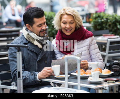 Personnes âgées heureux touristes ayant café au café et la lecture de la carte Banque D'Images