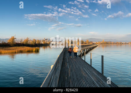 Vue paysage de Marais et lac avec la ville de Rapperswil dans la lumière du soir et d'une longue promenade en bois au premier plan et un couple f Banque D'Images