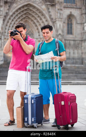 Deux hommes avec des valises sont à pied avec la carte et la photographie dans la rue à Barcelone. Banque D'Images