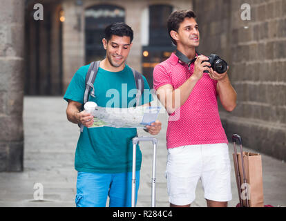 Portrait de deux hommes qui marchent avec la carte et la photographie dans la rue à Barcelone. Banque D'Images