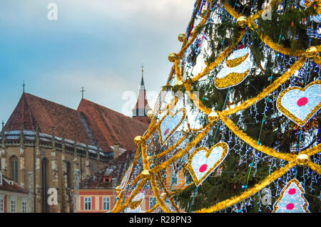 Un arbre décoré au Marché de Noël à Brasov. Vue vers l'Église Noire sur un soir de Décembre Banque D'Images