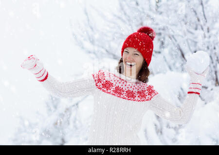 Jeune femme en chandail tricoté jouer snow ball fight en hiver. Famille Fille de boules de neige jeu. En fait main tricot femme chapeau et mitaines avec Christm Banque D'Images