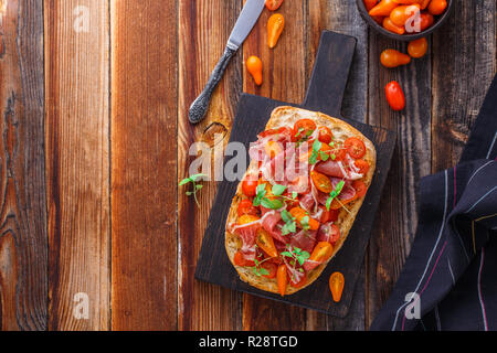 Antipasti italiens - chiabatta avec prosciutto, tomates cerises et basilic. Banque D'Images