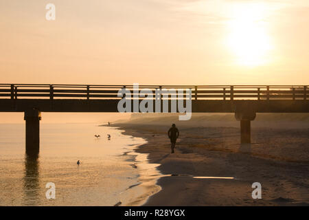 Prerow, Allemagne - 10 octobre 2018 : Le jogging alors que le soleil se lève le long de la mer Baltique, l'Allemagne. Banque D'Images