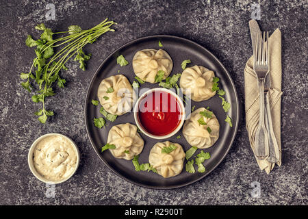 Khinkali boulettes à la vapeur traditionnel avec tomate et sauce tartare, vue d'en haut. Banque D'Images