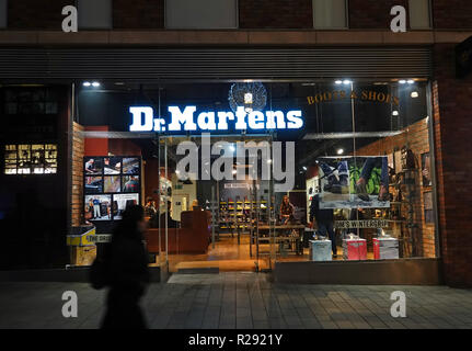 Les gens en silhouette en passant devant un magasin de Dr Martens dans centre commercial Liverpool One dans la nuit. Liverpool UK. Novembre 2018. Banque D'Images