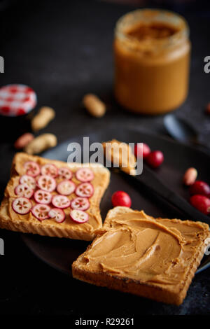 Toasts de pain avec beurre de cacahuète fait maison servi avec des tranches de canneberges fraîches Banque D'Images