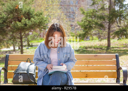 Jeune femme lisant sur un banc. Étudiant d'université. Banque D'Images
