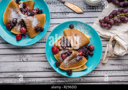 Des crêpes faites maison avec des baies congelées, garni de sucre, bois rustique, vintage photography Banque D'Images