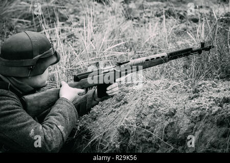 Gomel, Bélarus - 26 novembre 2017 : soldat de la Wehrmacht de la Seconde Guerre mondiale dans un casque avec un fusil dans ses mains dans une position tranchée. Le noir et blanc photogr Banque D'Images