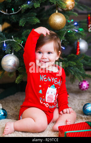 Noël photo de bébé en bonnet rouge. Les jours fériés et l'arbre de Noël. Banque D'Images