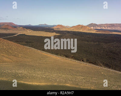 Vue aérienne de reliefs, les volcans et les champs de lave dans l'île de Lanzarote, îles Canaries, Espagne. Côte sauvage et la route qui longe l'île Banque D'Images