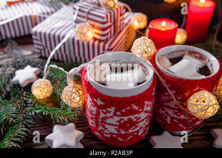 Chocolat chaud avec des guimauves et des biscuits sur les décorations de Noël arrière-plan. Guirlande et sapin Créer une atmosphère chaleureuse. Banque D'Images