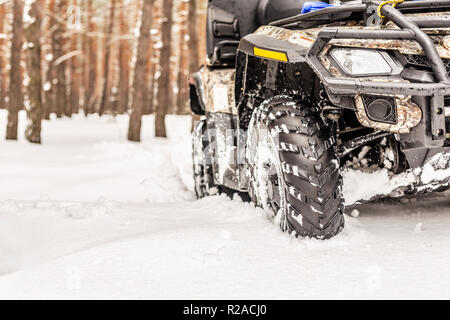 Close-up 4x4 ATV quad en forêt à l'hiver. Tous les 4RM-terreain stand véhicule dans la neige lourde avec l'écartement de voie profonde. Sport et aventure extrême saisonnières Voyage. Copyspace Banque D'Images
