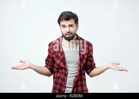 Confondre jeune homme habillé en noir chemise rouge debout sur fond blanc Banque D'Images