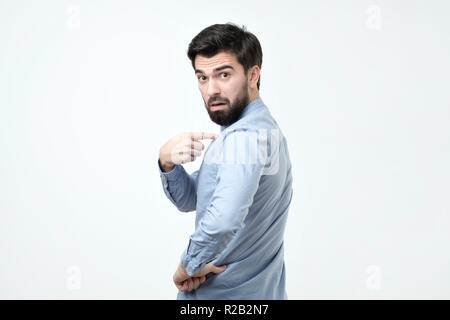 Beau jeune homme hispanique fronçant avec volume pointer du doigt et lui-même Banque D'Images