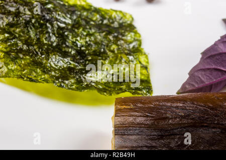 Still Life - orphie fumé avec de la chaux, le basilic, l'oignon vert, chili, nori chips, épices, huile d'olive dans un plat de céramique blanc, sur une table en bois Banque D'Images