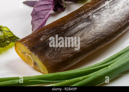 Still Life - orphie fumé avec de la chaux, le basilic, l'oignon vert, chili, nori chips, épices, huile d'olive dans un plat de céramique blanc, sur une table en bois Banque D'Images