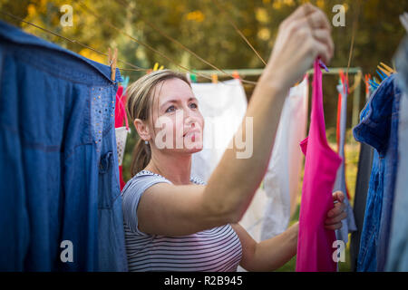 Jeune femme en mettant une corde à linge dans son jardin, en prenant bien soin de sa famille sur une base quotidienne Banque D'Images